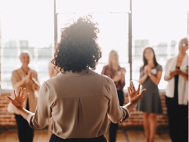 woman standing in front of other women giving a speech