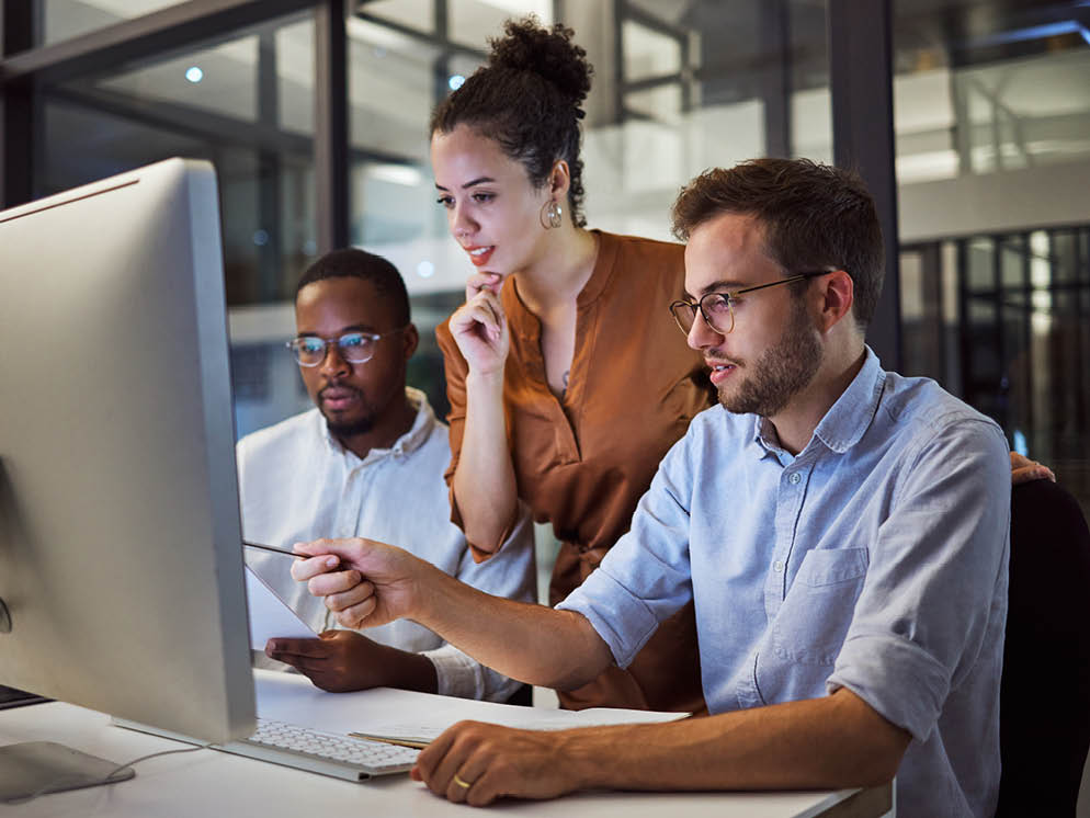 Three colleagues discussing while looking at a computer