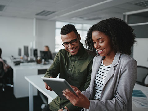 Professional young businesspeople using tablet computer smiling in office