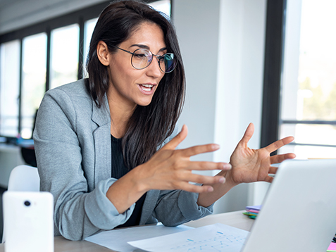 Shot of confident business woman looking and speaking through the webcam while making a video conference with laptop from the office.