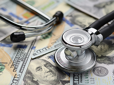 Medical stethoscope on heap of dollar bills. Health care or insurance costs concept. Finance banking audit analytics.