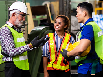 Man and Woman engineering wearing safety goggles and hard hats giving high five and celebrating success.