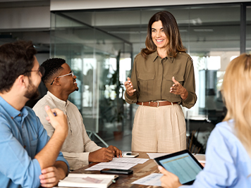 Happy middle aged business woman executive ceo leader discussing project management planning strategy working with diverse colleagues company team at office corporate board group meeting.