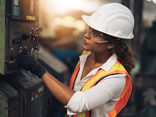 Woman manufacturing worker with a hard had and goggles on at a facility