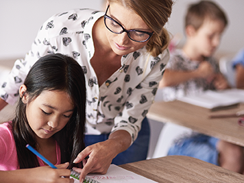 Teacher helping out a student with her work in a classroom.